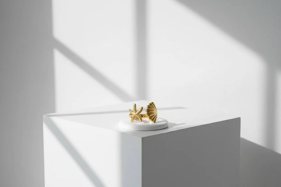 Starfish Gold Ring on a white pedestal with soft window-shadow lines, minimal bright lifestyle styling emphasizing the starfish and shell tips | OriaJewel