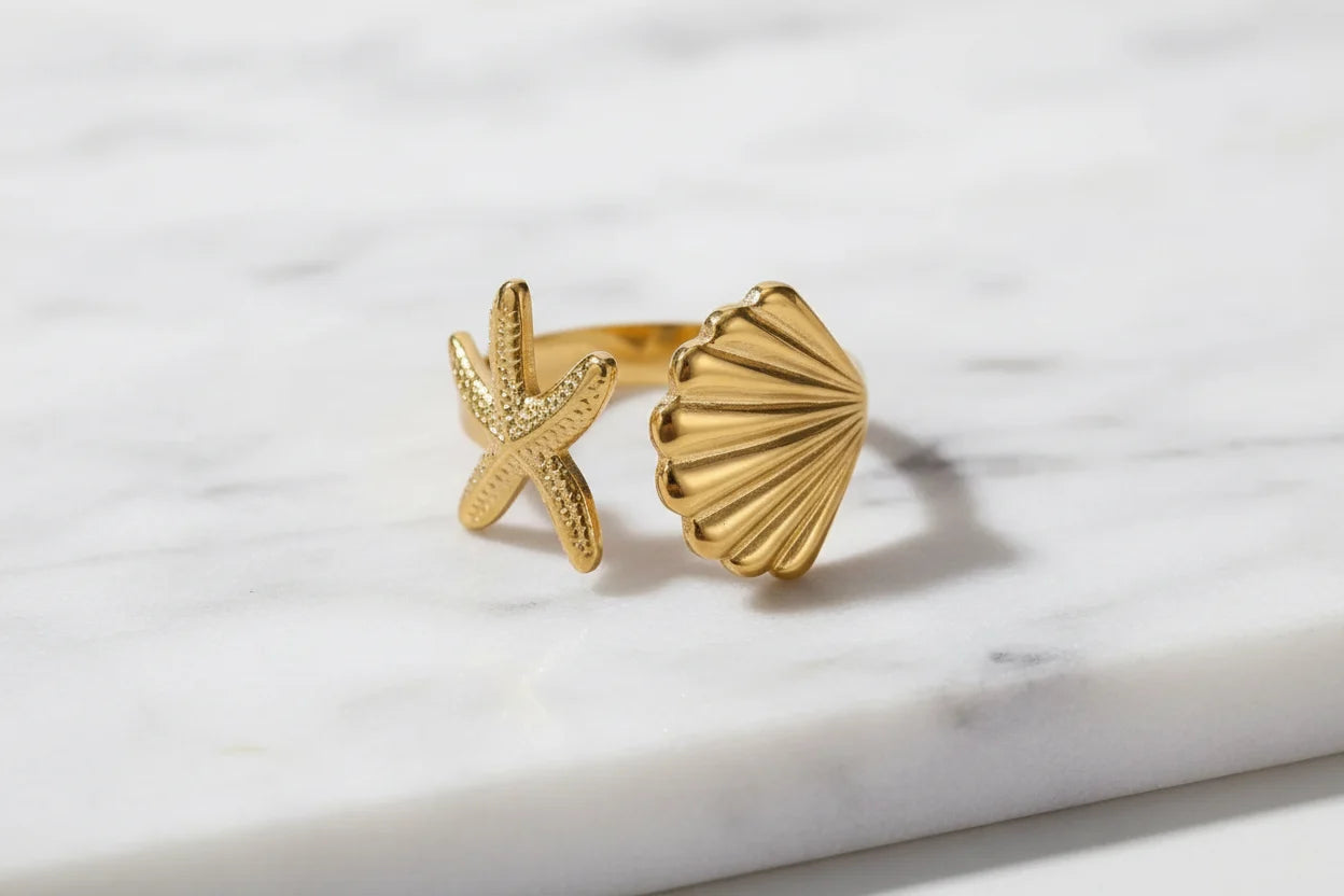 Starfish Gold Ring close-up on a marble surface, showing the polished gold-tone finish and textured starfish and shell design | OriaJewel
