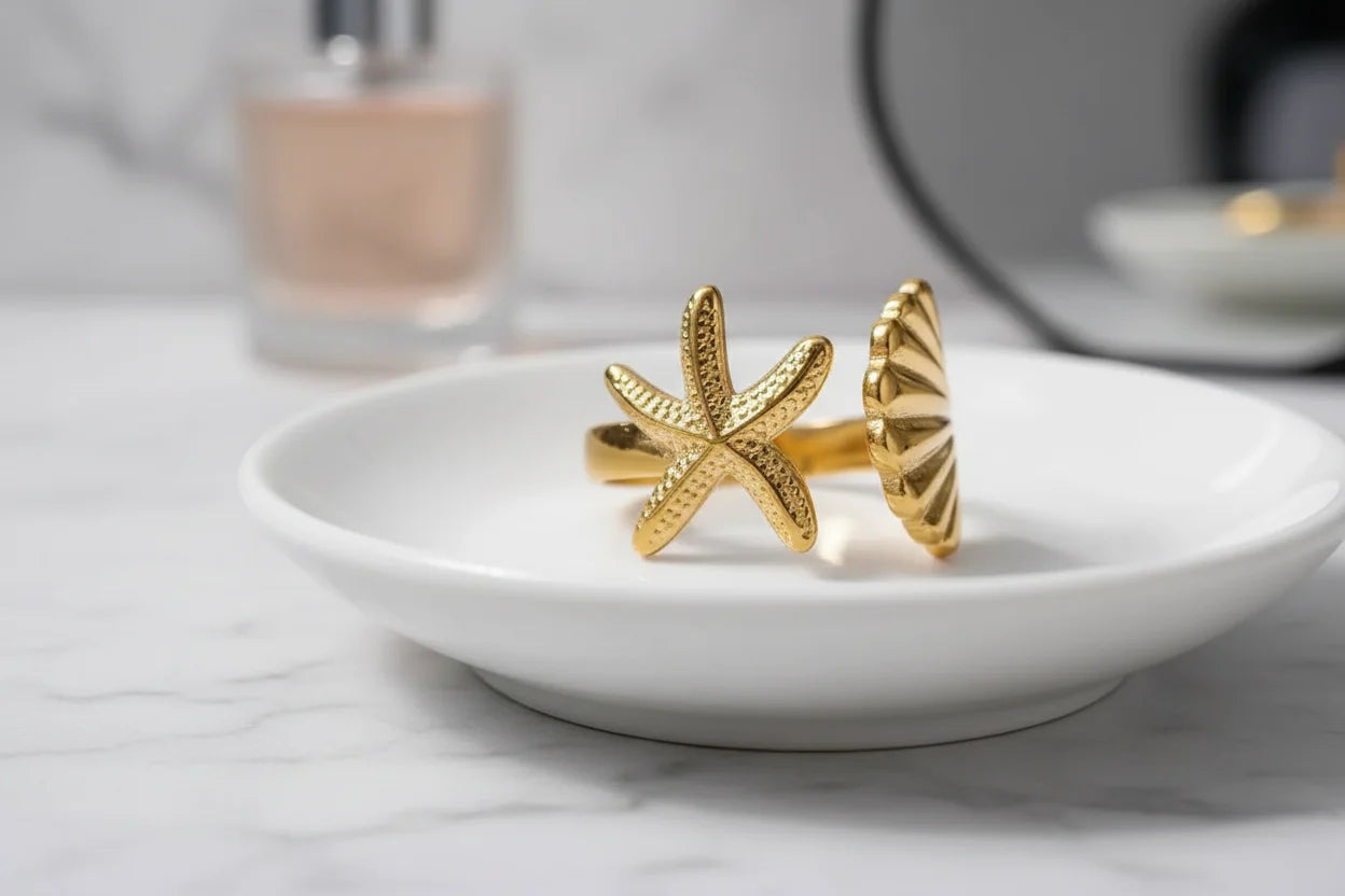 Starfish Gold Ring styled on a white dish with a perfume bottle and mirror softly blurred in the background, clean vanity lifestyle shot | OriaJewel