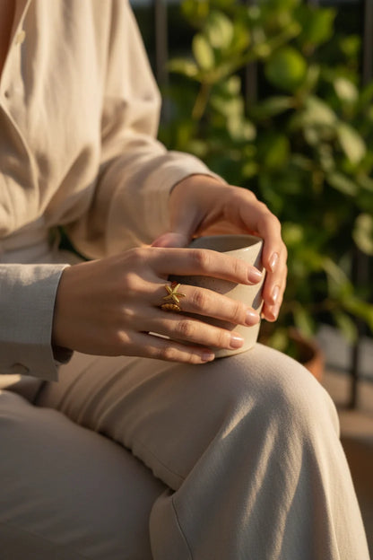 Starfish Gold Ring worn while holding a cup in warm outdoor light, subtle focus on the open ring’s starfish detail on the finger | OriaJewel