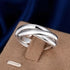 Shiny sterling silver crossover ring on tan display, dark blue background | Oria Jewel 