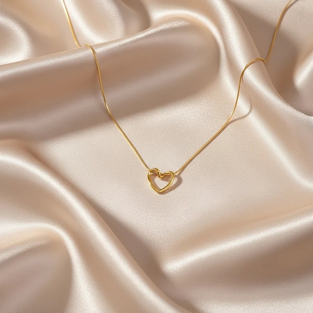 Gold-toned Sterling Silver Heart Chain Necklace on satin fabric — soft lighting accentuating heart-shaped pendant | Oria Jewel