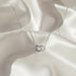 Minimalist Sterling Silver Heart Chain Necklace displayed on soft satin fabric — delicate shine and romantic design | Oria Jewel