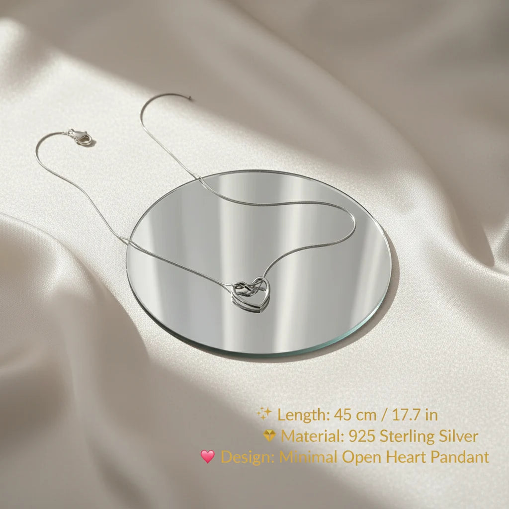 Sterling Silver Heart Chain Necklace displayed on a mirror over satin fabric with elegant text showing specifications — 45 cm / 17.7 in length, 925 sterling silver material, and minimal open heart pendant design | Oria Jewel