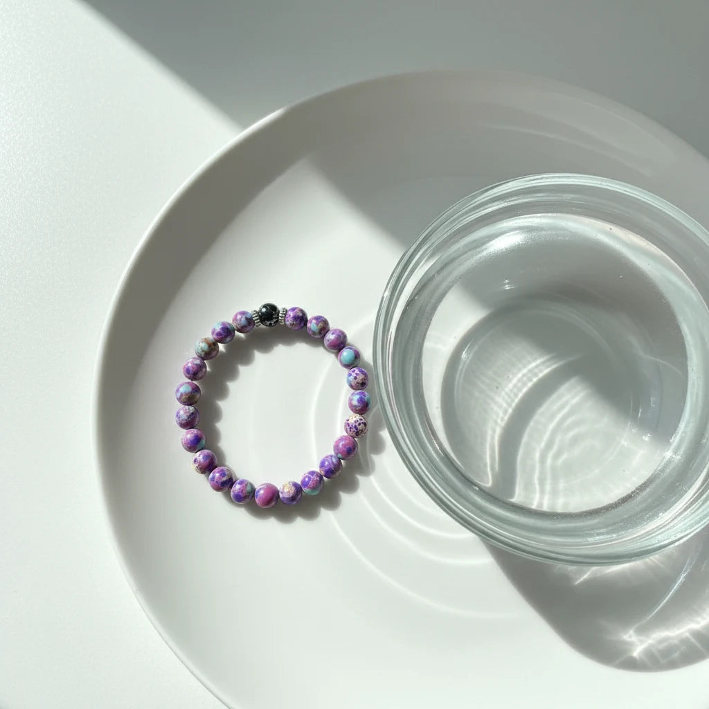 Stress Relief Gemstone Bracelet styled on a white plate next to a clear glass bowl in bright natural light | Oria Jewel