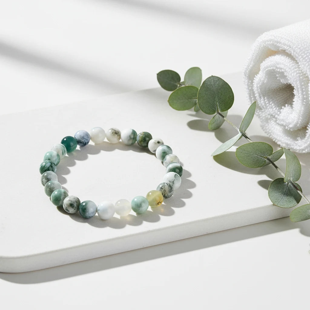 Spa-inspired scene with the Success Energy Stone Bracelet placed on a white tray beside rolled towels and eucalyptus leaves, suggesting cleansing, relaxation, and balanced energy | Oria Jewel