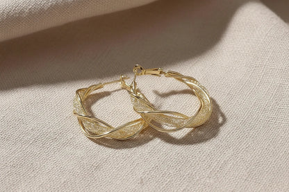 Twisted Crossover Hoop Earrings on linen fabric close-up | OriaJewel