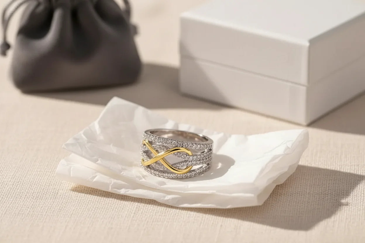 Two Tone Criss Cross Ring styled on crinkled tissue paper with a drawstring pouch and white jewelry box in the background, soft sunlight showcasing the sparkle and two-tone contrast | OriaJewel