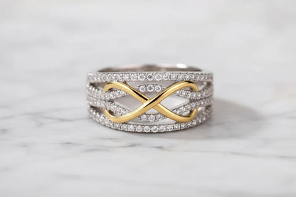 Two Tone Criss Cross Ring front-on product shot on a soft white surface, crisp focus on the intertwined gold ribbon design and shimmering pavé rows across the wide band | OriaJewel