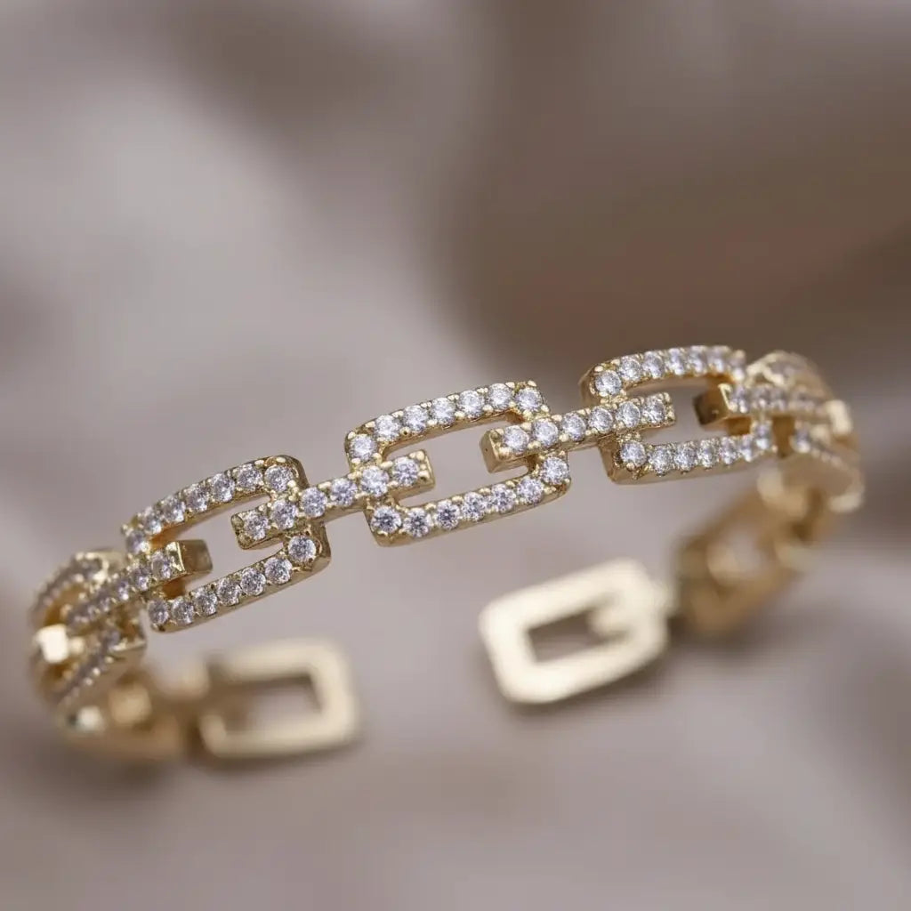 Macro shot of the Veluxa Pavé Link Cuff in gold, emphasizing rectangular pavé links and intricate detailing against a blurred satin backdrop | Oria Jewel