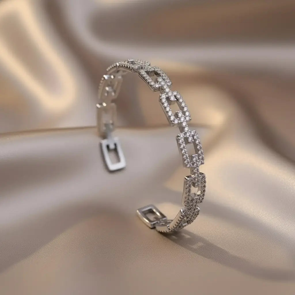 Veluxa Pavé Link Cuff in silver displayed on soft satin, showcasing shimmering pavé links and modern open design for cool-toned elegance | Oria Jewel