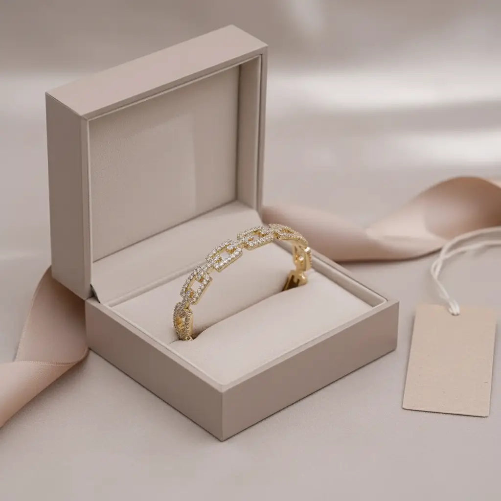 Gift-ready Veluxa Pavé Link Cuff in gold presented inside a cushioned beige jewelry box with ribbon and blank tag beside it | Oria Jewel