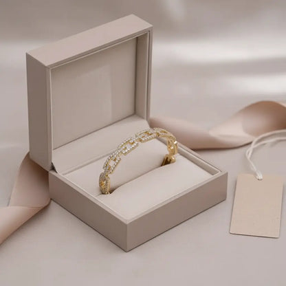 Gift-ready Veluxa Pavé Link Cuff in gold presented inside a cushioned beige jewelry box with ribbon and blank tag beside it | Oria Jewel
