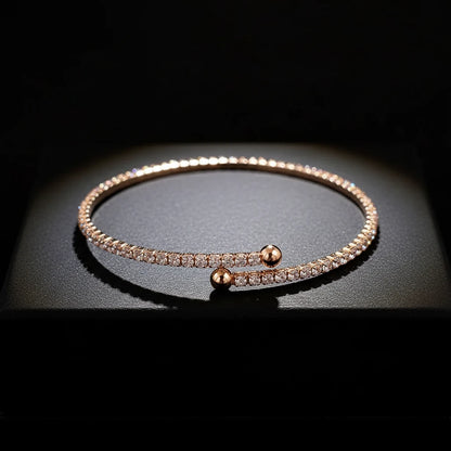 Veluxa Pavé Wrap Cuff in rose gold displayed on a dark pedestal, sparkling cubic zirconia catching dramatic studio light | Oria Jewel