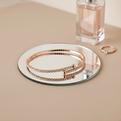 Veluxa Pavé Wrap Cuff placed on a round mirror tray with perfume bottle and ring, creating a chic vanity flatlay | Oria Jewel

