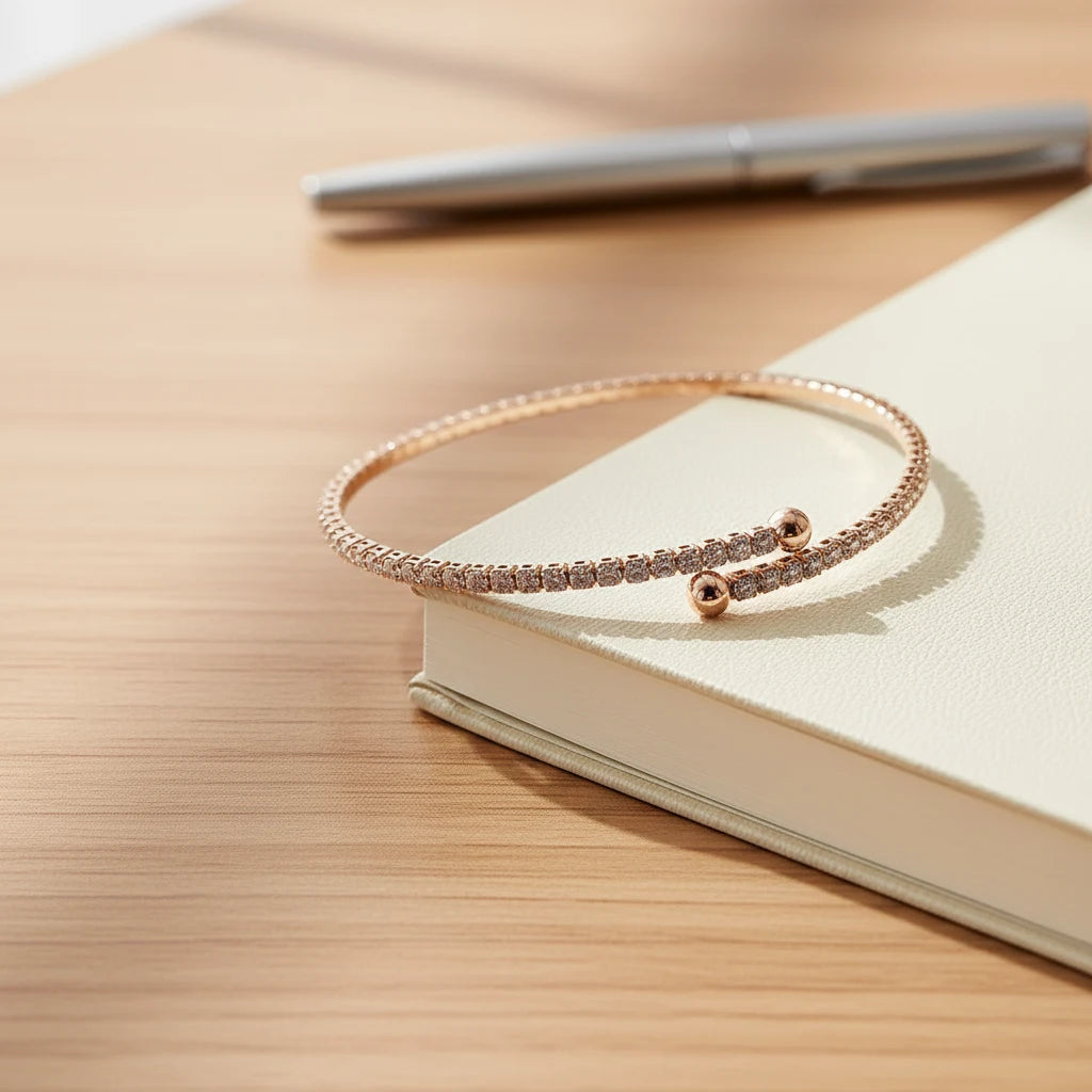 Veluxa Pavé Wrap Cuff in rose gold resting beside a notebook and pen on a wooden desk, styled for everyday elegance | Oria Jewel