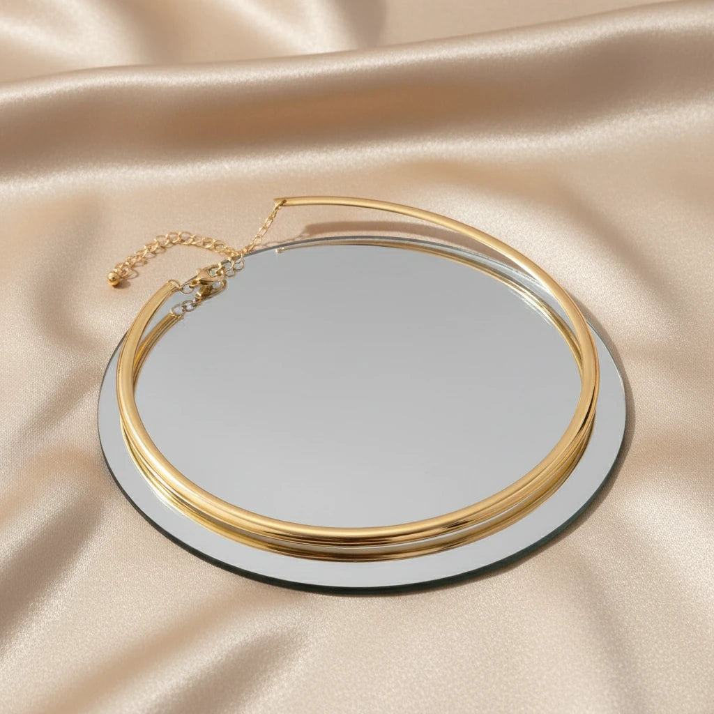 Vintage Choker Necklace in gold arranged on round mirror with warm reflections and satin background | Oria Jewel