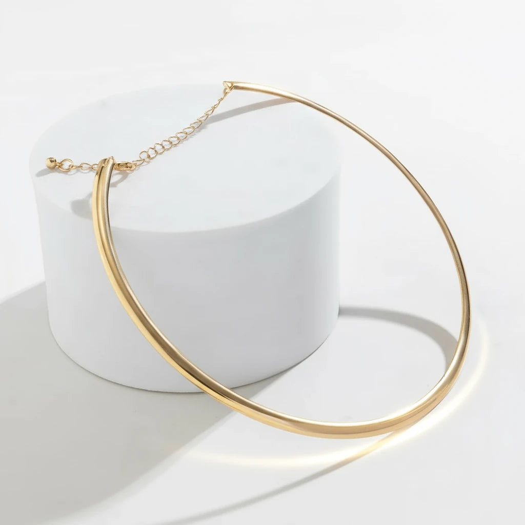 Vintage Choker Necklace in gold resting on white circular stand with minimal lighting for modern aesthetic | Oria Jewel