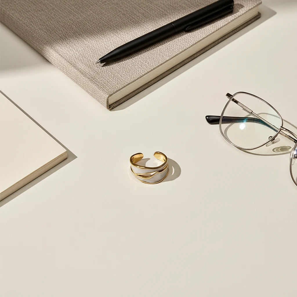 White Enamel Open Wave Ring minimal flat-lay on a clean desk with a notebook, pen, and eyeglasses, centered to show the open wave band and white enamel shine | OriaJewel