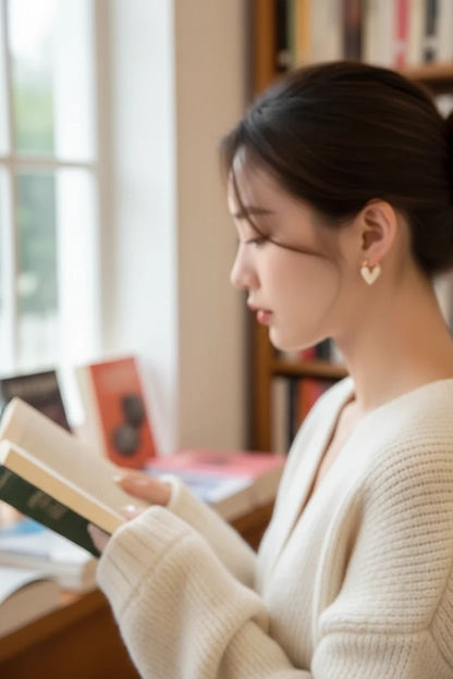 White Heart Huggie Hoop Earrings worn on model reading by window | OriaJewel