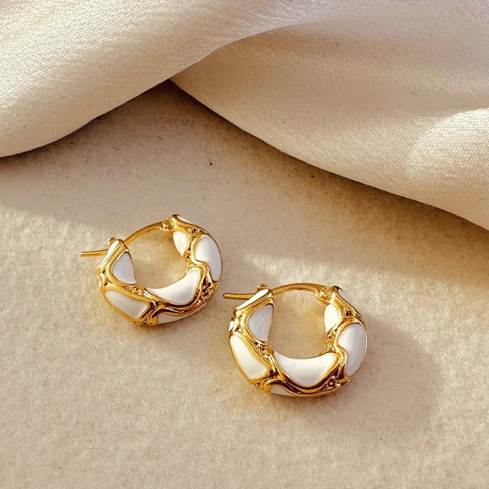 White Huggie Hoop Earrings close-up on satin fabric with gold details | OriaJewel