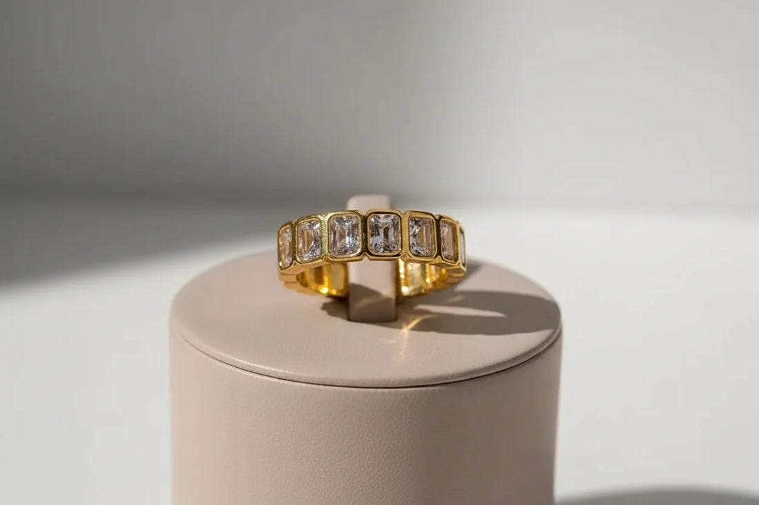 White stone band ring on a round beige display stand, sunlit product shot with sharp shadow lines for a modern, editorial jewelry look | OriaJewel