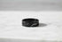 Wide Black Band Ring close-up on a light marble surface, focusing on the wide profile and clean geometric groove detail with soft highlights and a gentle shadow | OriaJewel