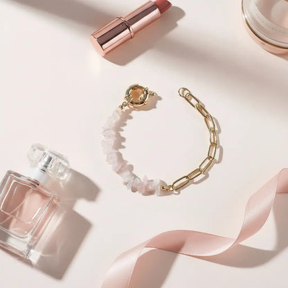 Rose-toned flat lay featuring a gold chain and pale pink gemstone chip amethyst bead bracelet arranged with a perfume bottle, lipstick and ribbon on a blush background for a romantic, feminine vibe | Oria Jewel