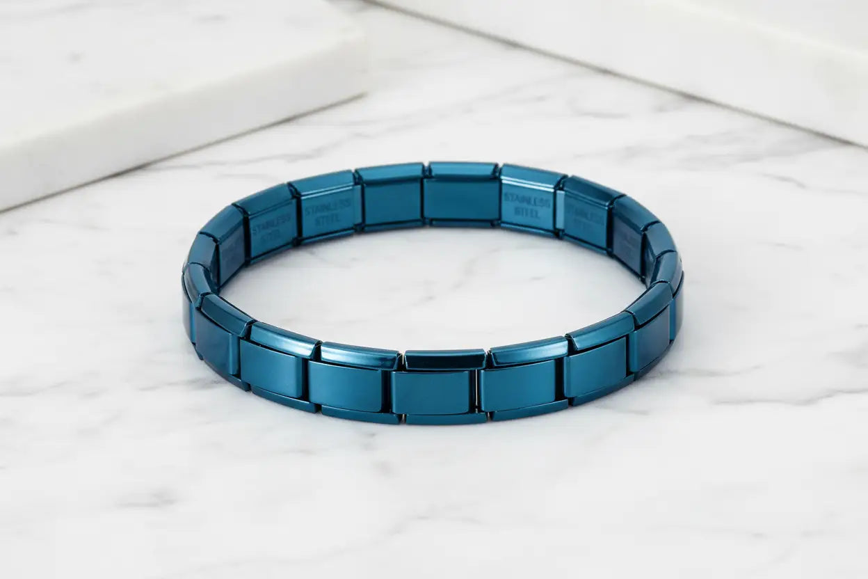 Minimal studio shot of a circular blue stainless steel stretch bracelets laid flat on a white marble surface, the glossy blue links reflecting soft light to emphasize the smooth, durable stainless-steel finish | Oria Jewel
