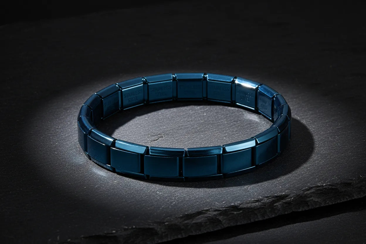 Dramatic dark studio scene with a spotlight focused on a single blue stainless steel stretch bracelets resting on a textured slate surface, highlighting the deep blue metallic tone and bold, minimalist design | Oria Jewel