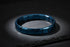 Dramatic dark studio scene with a spotlight focused on a single blue stainless steel stretch bracelets resting on a textured slate surface, highlighting the deep blue metallic tone and bold, minimalist design | Oria Jewel