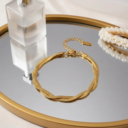Elegant vanity scene with a double chain gold bracelet resting on a round mirrored tray next to a frosted perfume bottle and pearl accessory | Oria Jewel