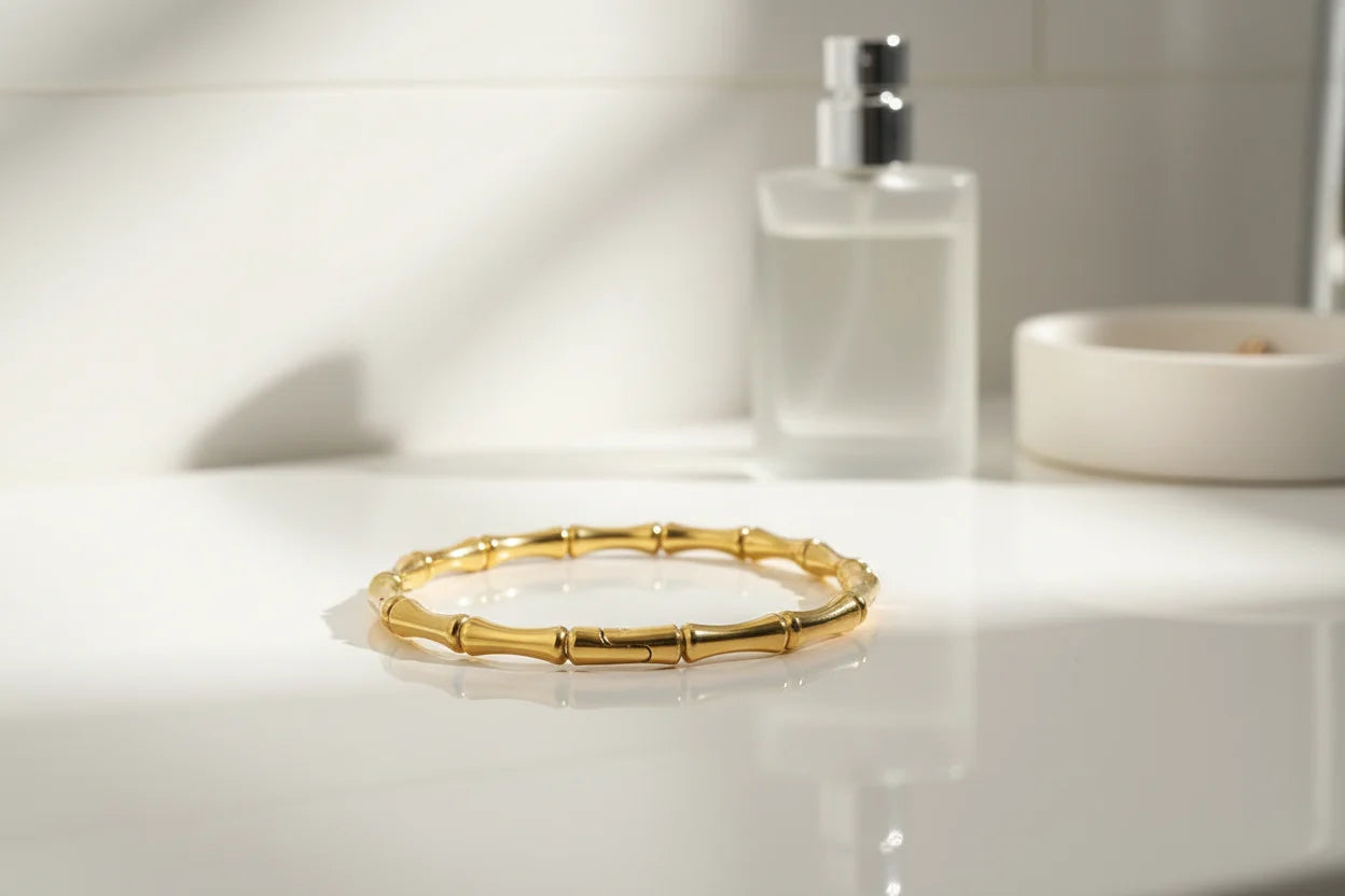 Gold Bamboo bangle Bracelet displayed on a white bathroom vanity next to a perfume bottle and ceramic dish, styled as an elegant morning getting-ready setup | Oria Jewel