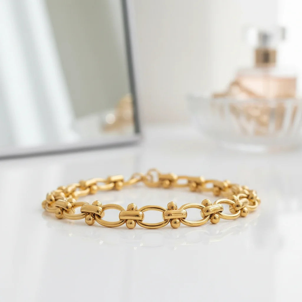 Glamorous vanity scene with a gold chain link bracelet resting in front of a mirror and perfume bottles, reflecting a feminine, getting-ready moment | Oria Jewel