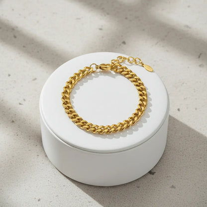 Minimal gold curb chain bracelet showcased on a round white jewelry box with soft natural light and subtle shadows | Oria Jewel
