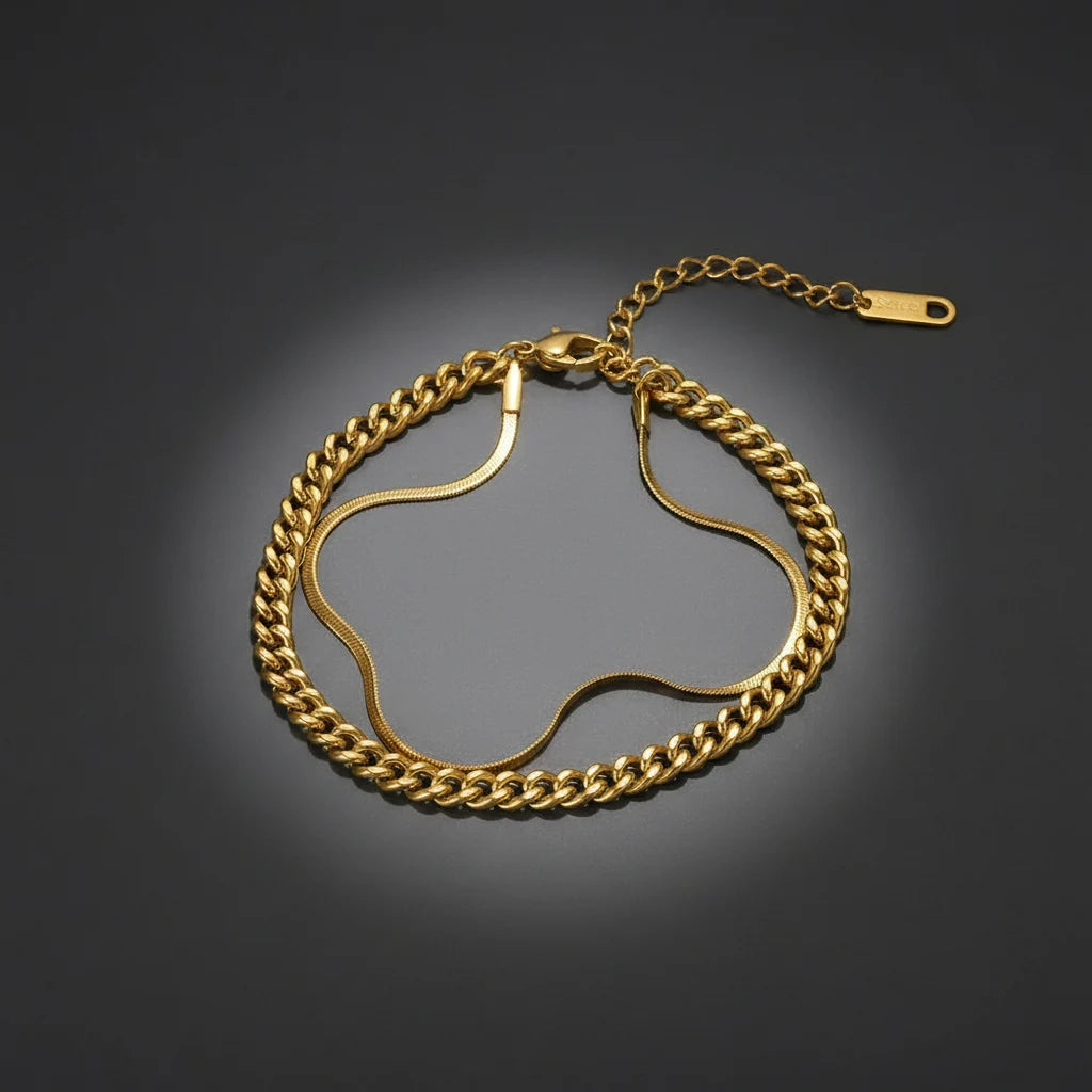Dramatic studio shot of gold double chain bracelet on dark background with spotlight glow, showcasing bold golden shine | Oria Jewel
