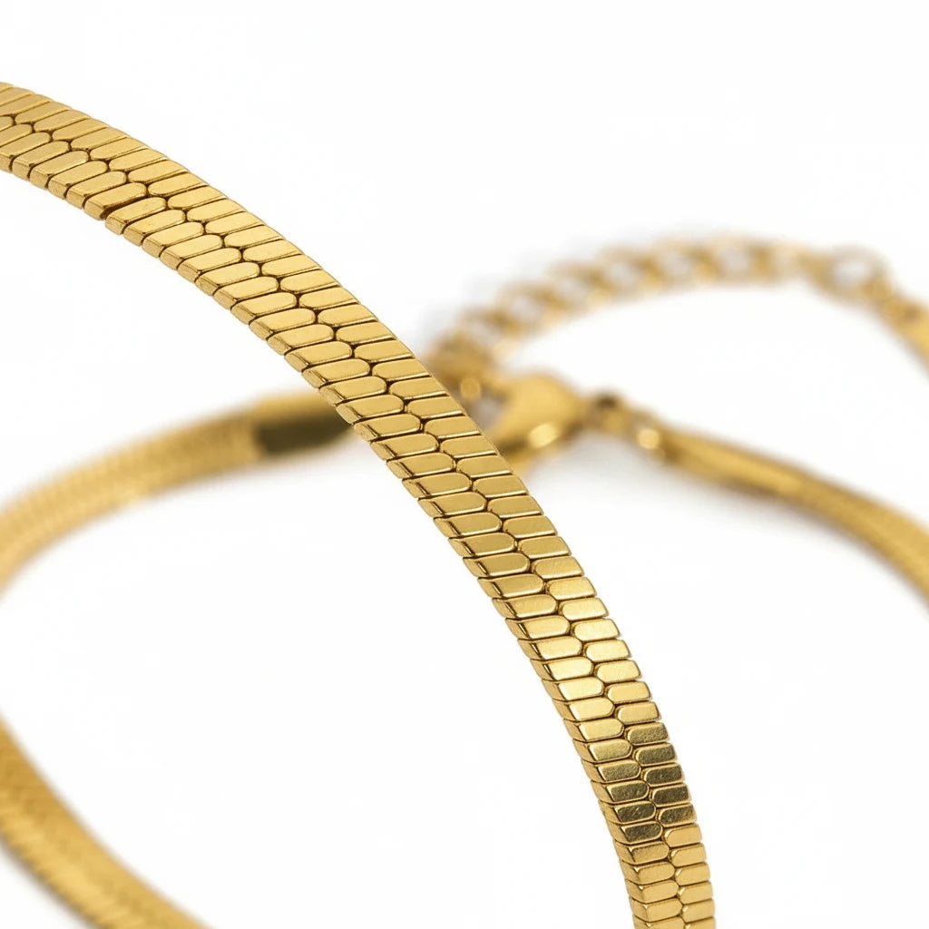 Close-up macro view of the flat textured links of a gold herringbone chain bracelet highlighting its smooth, flexible snake-like pattern | Oria Jewel