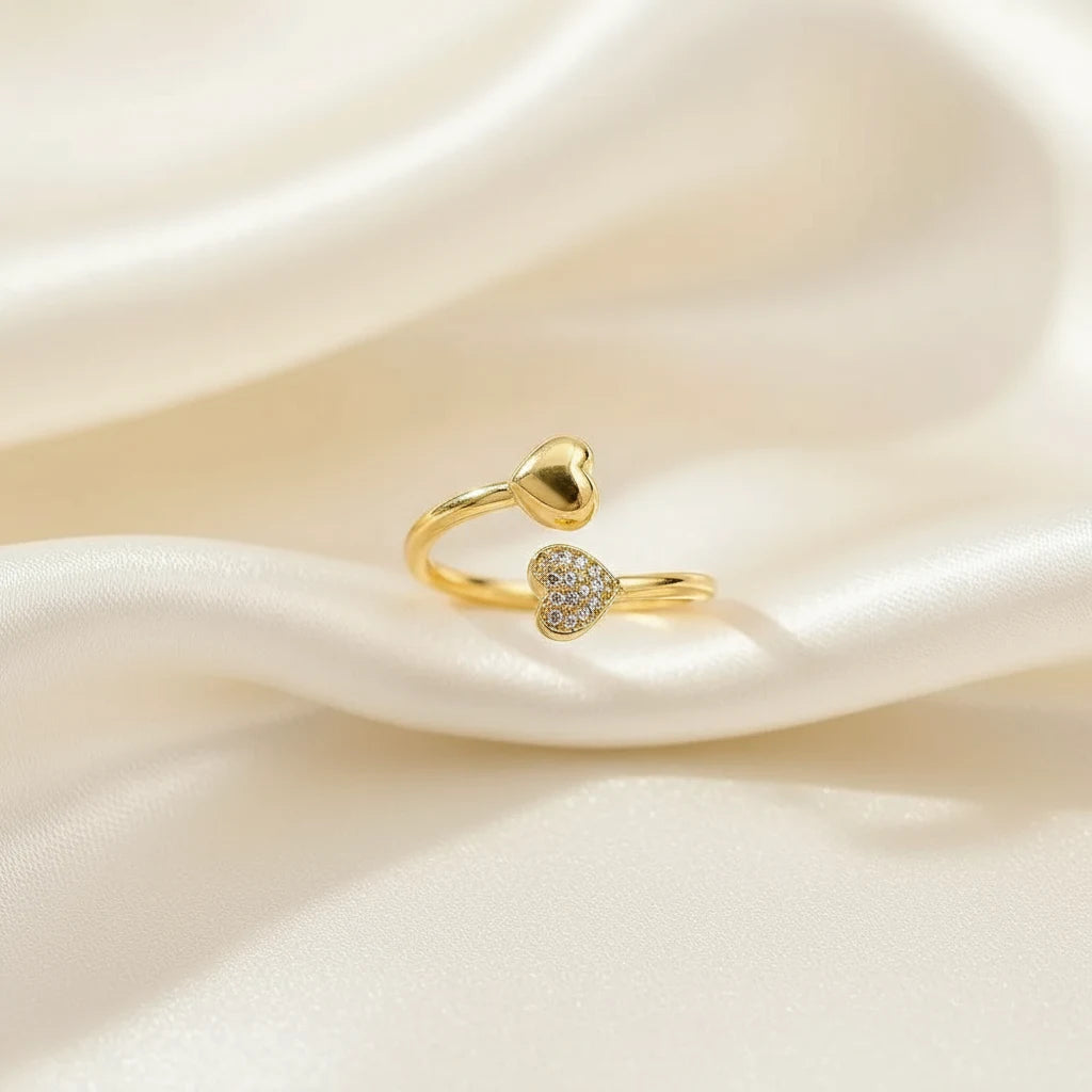 gold open heart ring with pavé crystal heart tip and smooth heart end on soft ivory satin folds, macro product photo | Oria Jewel