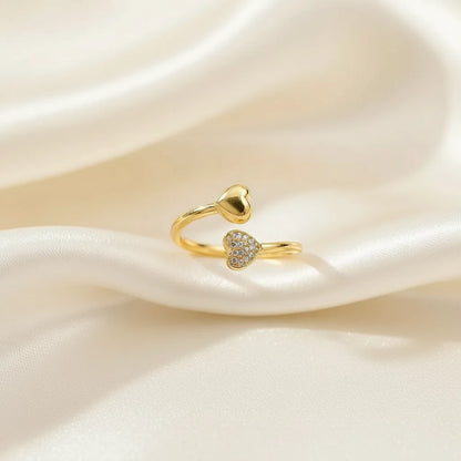 gold open heart ring with pavé crystal heart tip and smooth heart end on soft ivory satin folds, macro product photo | Oria Jewel
