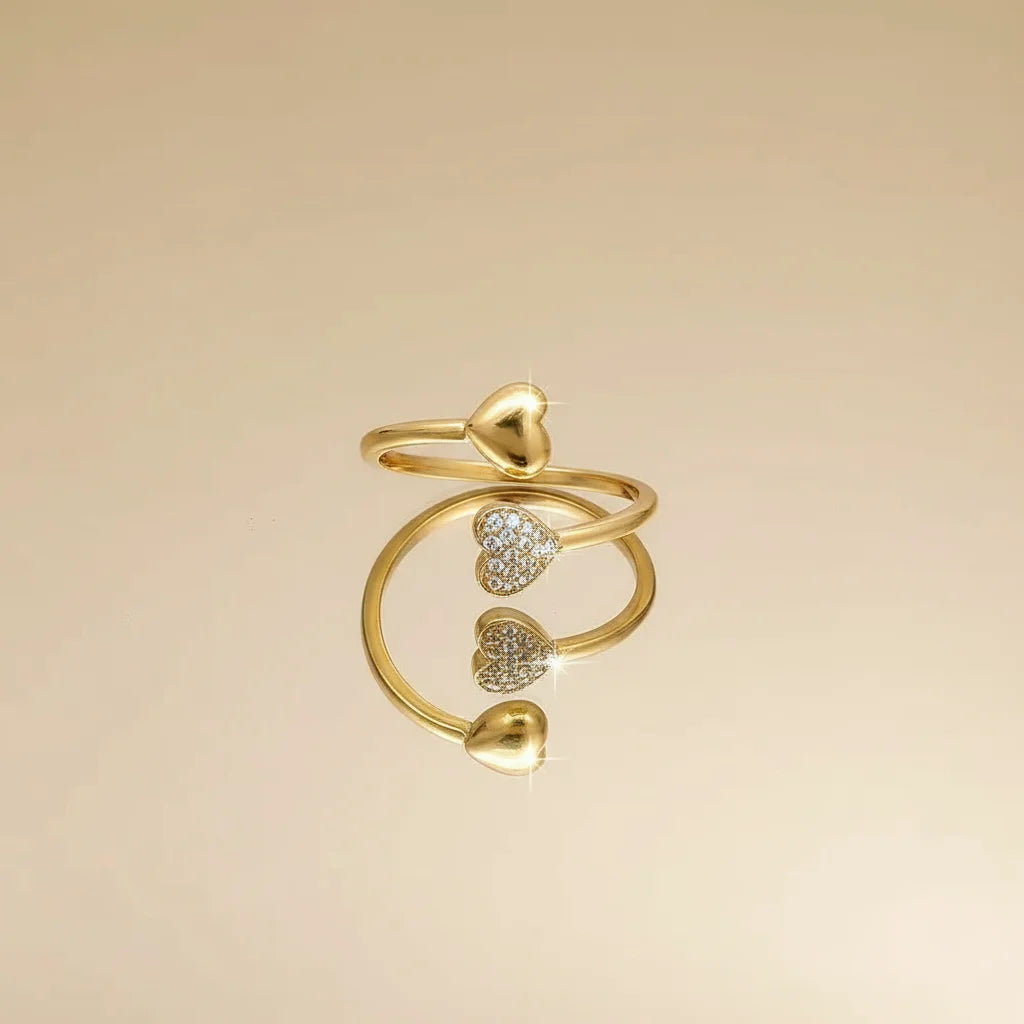 gold open heart ring styled as a spiral wrap with multiple heart tips, mix of polished and pavé hearts on warm beige background | Oria Jewel