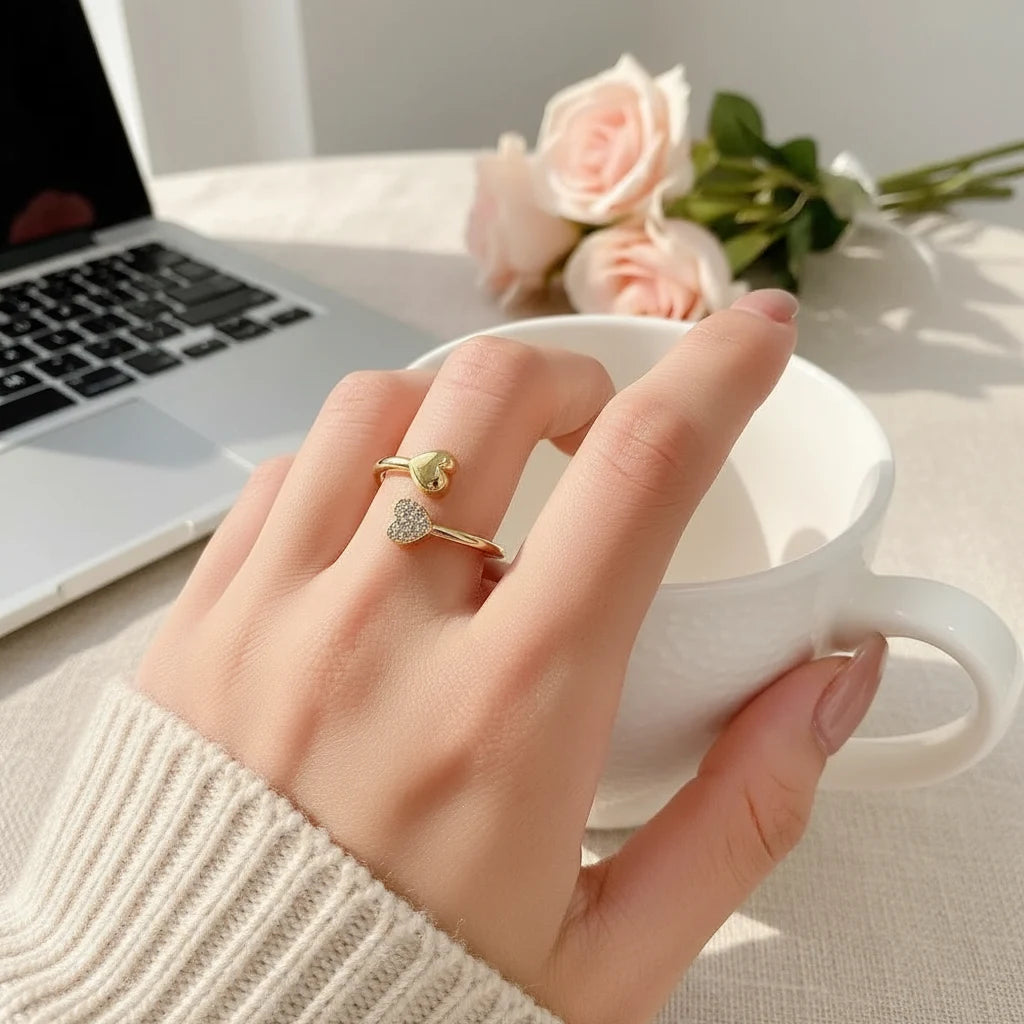 gold open heart ring on hand holding a white cup near a laptop and pink roses, delicate open heart look with pavé sparkle | Oria Jewel