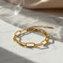 Minimal studio shot of a gold paperclip chain bracelet with extender chain resting on white marble in soft sunlight | Oria Jewel