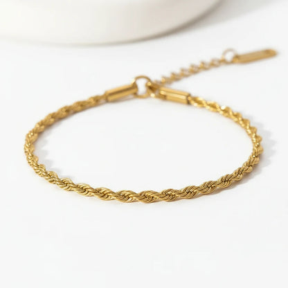 Minimal studio close-up of a delicate gold rope chain bracelet arranged in a circle on a clean white background with soft light and shadows | Oria Jewel