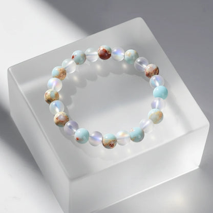 Minimal studio shot of the Luck &amp; Health Stone Bracelet displayed on a frosted acrylic block, with soft shadows emphasizing the glossy round beads | Oria Jewel