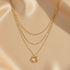 Close-up of Multi Layered Gold Chain Necklace on soft satin fabric — 18K gold shine with twisted pendant detail | Oria Jewel