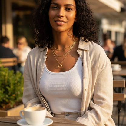 Woman in café wearing Multi Layered Gold Chain Necklace layered over white tank and beige shirt — effortless everyday chic | Oria Jewel