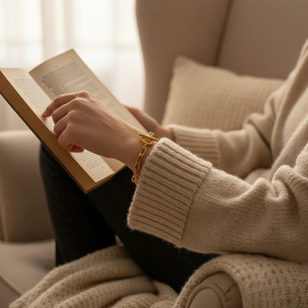 Lifestyle close-up of a woman reading in a knit sweater, showcasing the oval link chain bracelet on her wrist for a relaxed cozy look | Oria Jewel