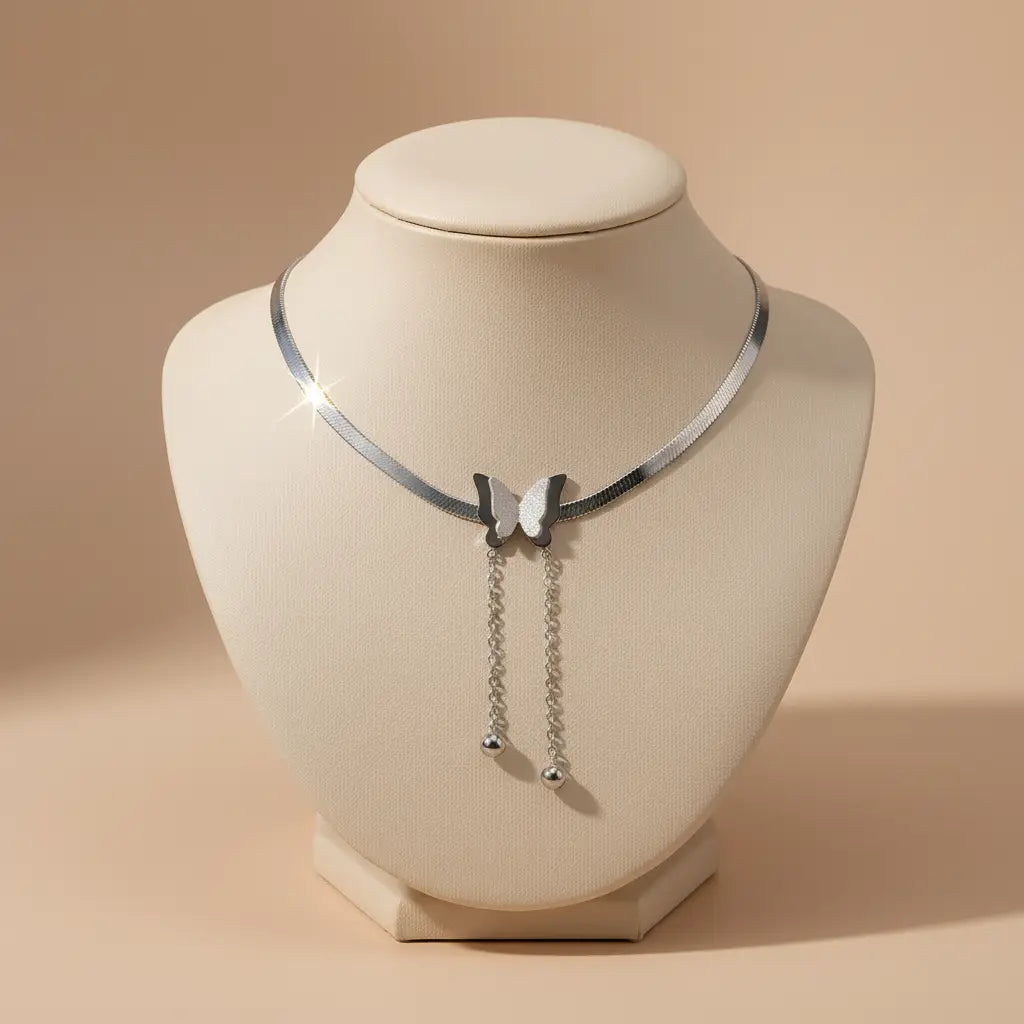 Minimal display bust showing sleek Silver Butterfly Chain Necklace with dangling chains and ball charms on beige background | Oria Jewel