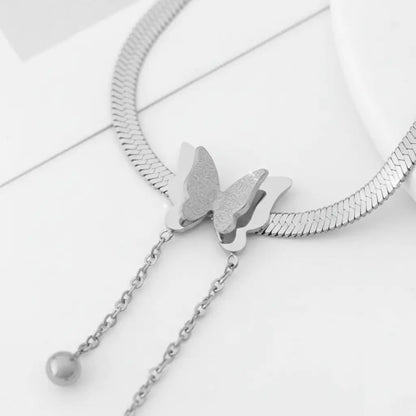 Macro shot of pendant section of Silver Butterfly Chain Necklace highlighting textured butterfly wings and smooth chain tassels | Oria Jewel
