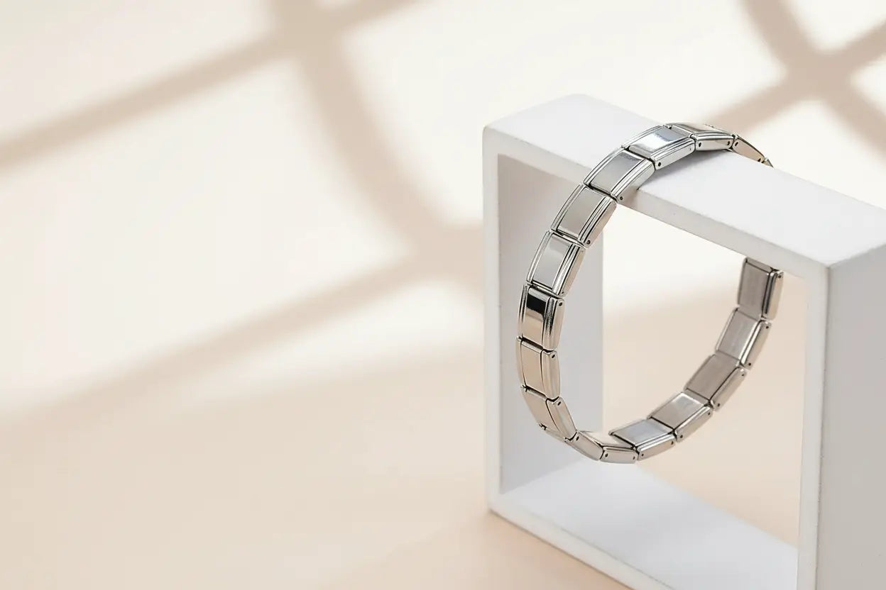 Minimalist studio shot of a single silver stainless steel stretch bracelets bracelets draped over a white geometric frame, with soft shadows emphasizing its smooth, reflective links and flexible stretch design | Oria Jewel